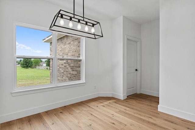unfurnished dining area with baseboards and light wood-style flooring