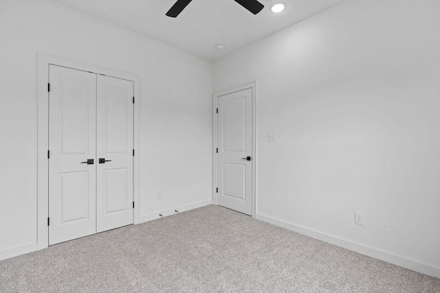 unfurnished bedroom featuring carpet, a closet, baseboards, and ceiling fan
