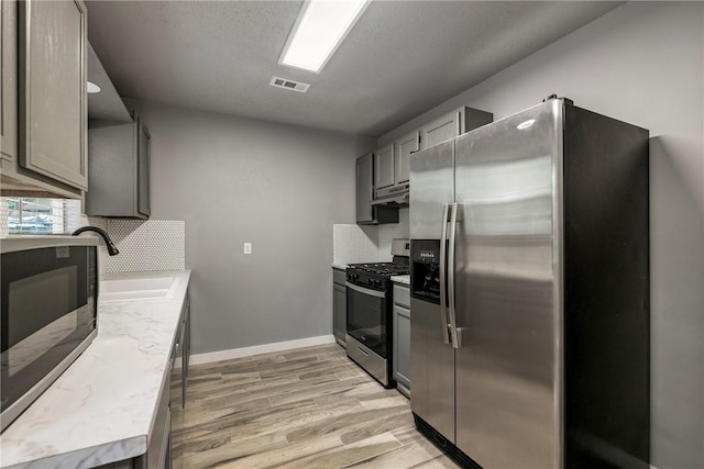 kitchen with visible vents, a sink, light countertops, tasteful backsplash, and appliances with stainless steel finishes