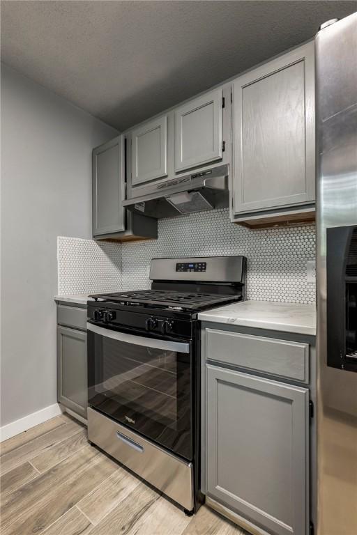 kitchen featuring under cabinet range hood, appliances with stainless steel finishes, and gray cabinets