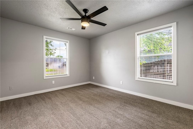 unfurnished room with baseboards, a healthy amount of sunlight, dark colored carpet, and a textured ceiling