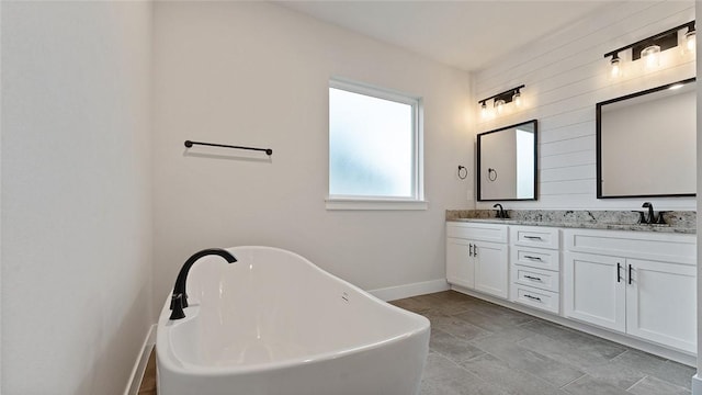 bathroom with baseboards, double vanity, and a soaking tub