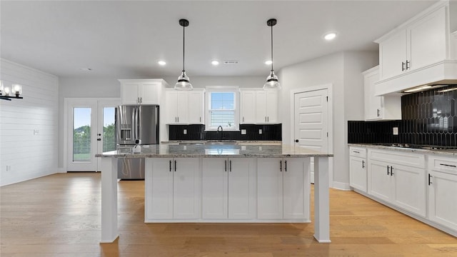 kitchen with stainless steel refrigerator with ice dispenser, a sink, gas cooktop, decorative backsplash, and a center island