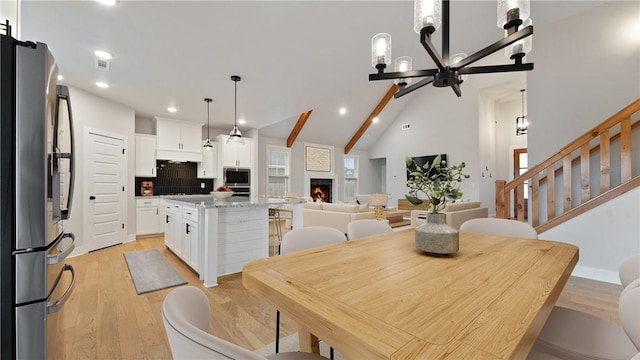 dining area featuring a chandelier, light wood-type flooring, recessed lighting, a fireplace, and stairway