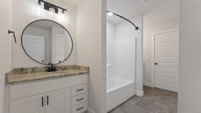 bathroom featuring shower / washtub combination, vanity, baseboards, and stone finish floors