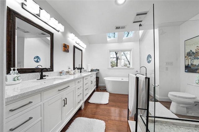 5008 Cliff Dr, Fort Smith, AR 72903 - full bathroom with a skylight, double vanity, wood finished floors, a freestanding tub, and toilet