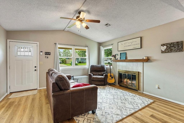 1165 Massey St, Decatur, AR 72722 - living room with lofted ceiling, ceiling fan, visible vents, wood finished floors, and a tile fireplace