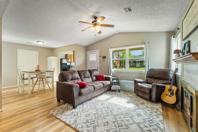 1165 Massey St, Decatur, AR 72722 - living room featuring a textured ceiling, ceiling fan, visible vents, a tile fireplace, and light wood-type flooring