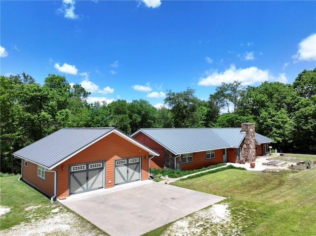 view of front of house featuring a chimney, driveway, an outbuilding, a garage, and a front lawn