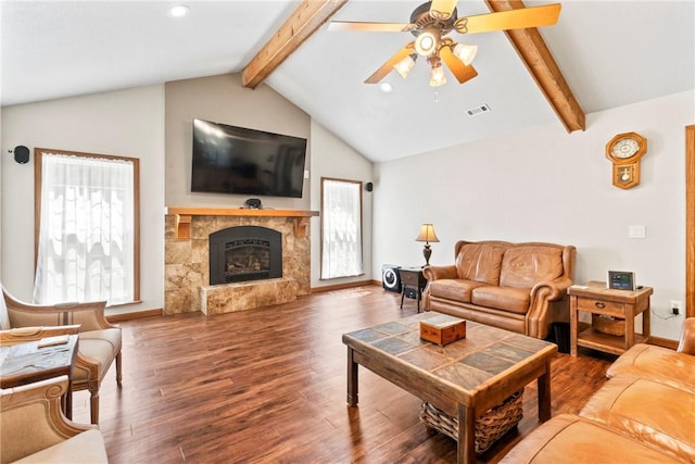 living room with ceiling fan, lofted ceiling with beams, a tiled fireplace, and wood finished floors