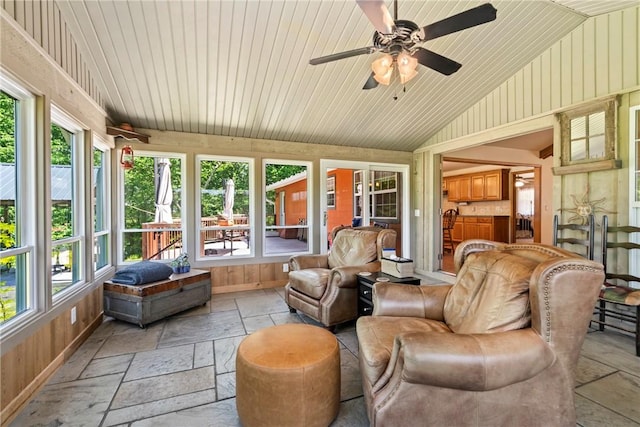 sunroom / solarium with a wealth of natural light, lofted ceiling, and stone tile floors