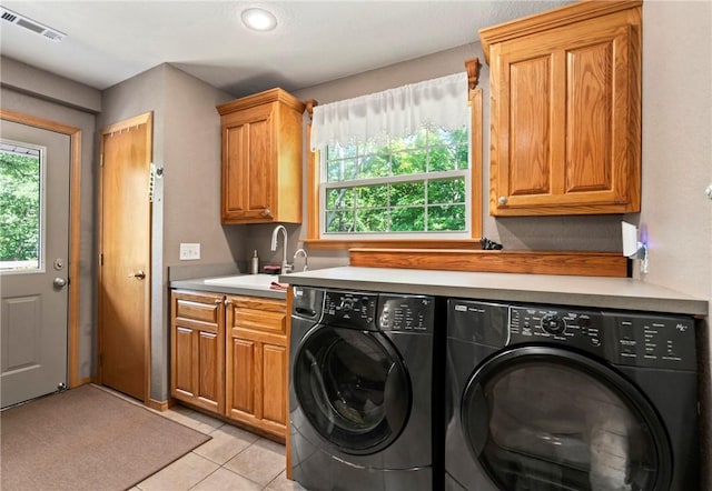 laundry area featuring a sink, cabinet space, visible vents, independent washer and dryer, and light tile patterned flooring