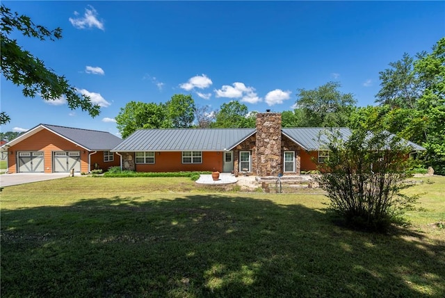 view of front of property with driveway, a garage, a front yard, metal roof, and a chimney