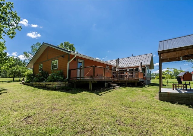 rear view of property featuring metal roof, a wooden deck, and a lawn