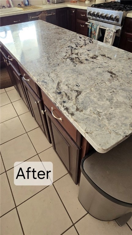 kitchen with light stone counters, light tile patterned floors, and stainless steel range