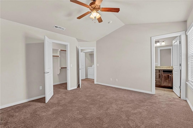 unfurnished bedroom with vaulted ceiling, independent washer and dryer, light carpet, and visible vents