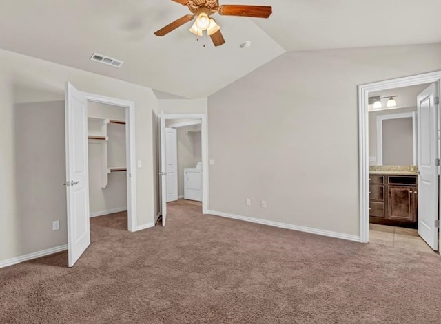 unfurnished bedroom with lofted ceiling, light carpet, a spacious closet, and washer / dryer