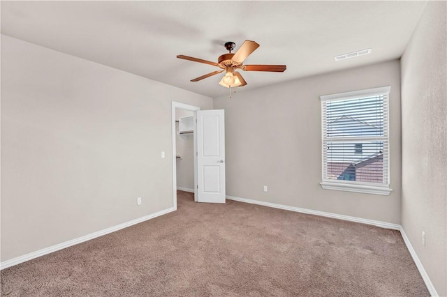 carpeted empty room with a ceiling fan, baseboards, and visible vents