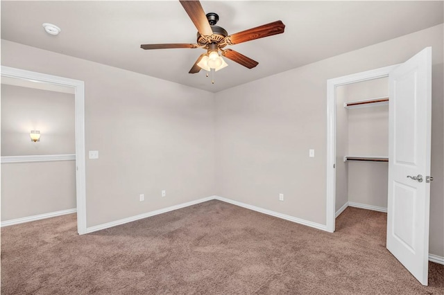 unfurnished bedroom with baseboards, carpet floors, and a walk in closet