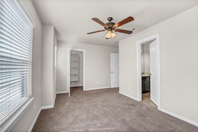 unfurnished bedroom featuring multiple windows, light carpet, baseboards, and a spacious closet