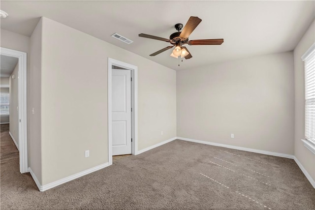 carpeted spare room featuring baseboards, a ceiling fan, and visible vents