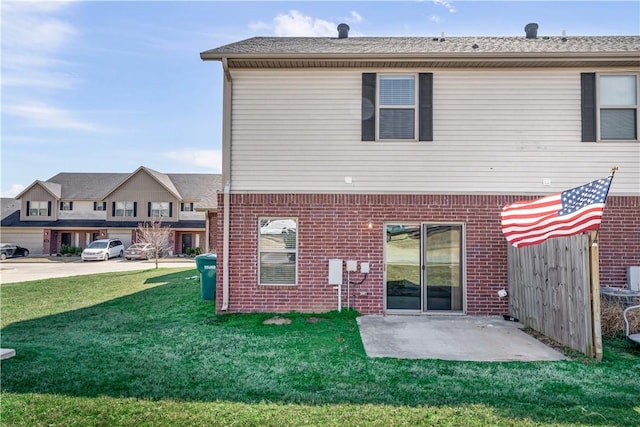 back of property featuring fence, a patio, brick siding, and a lawn