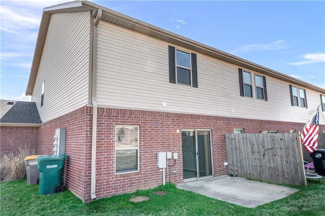 rear view of property with brick siding, fence, and a patio