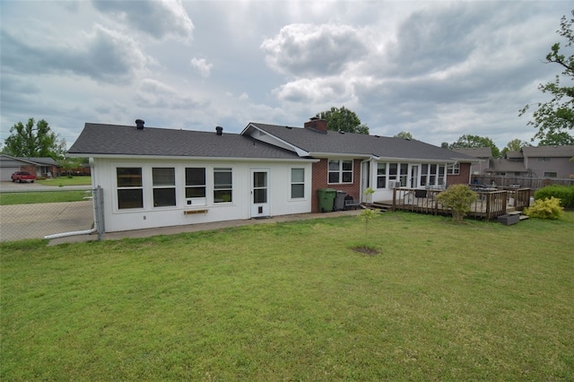 back of property with a yard, a chimney, and a deck