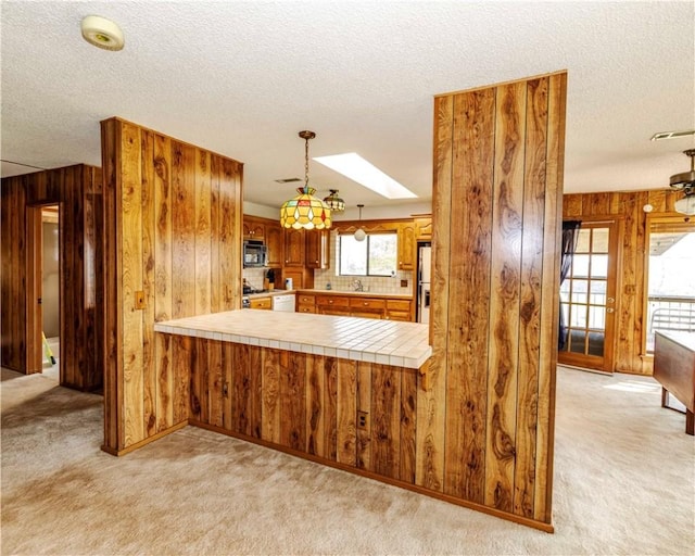 315 N Letitia Ave, Fayetteville, AR 72701 - kitchen featuring stainless steel microwave, wooden walls, a textured ceiling, light colored carpet, and a peninsula