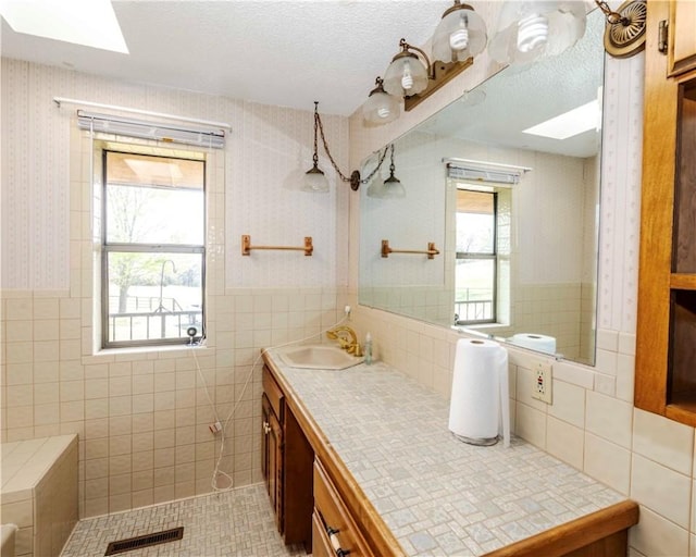 315 N Letitia Ave, Fayetteville, AR 72701 - bathroom with a skylight, wallpapered walls, tile walls, vanity, and wainscoting
