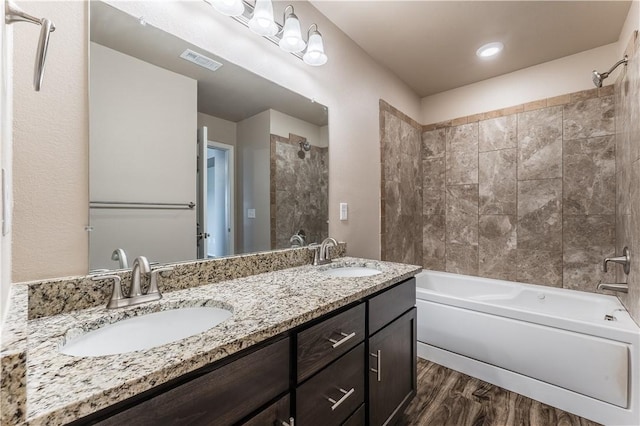 full bath featuring shower / washtub combination, visible vents, wood finished floors, and a sink