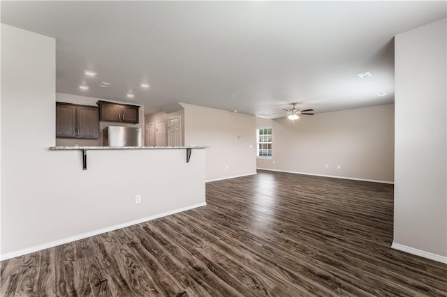 unfurnished living room featuring a ceiling fan, baseboards, recessed lighting, and dark wood-type flooring