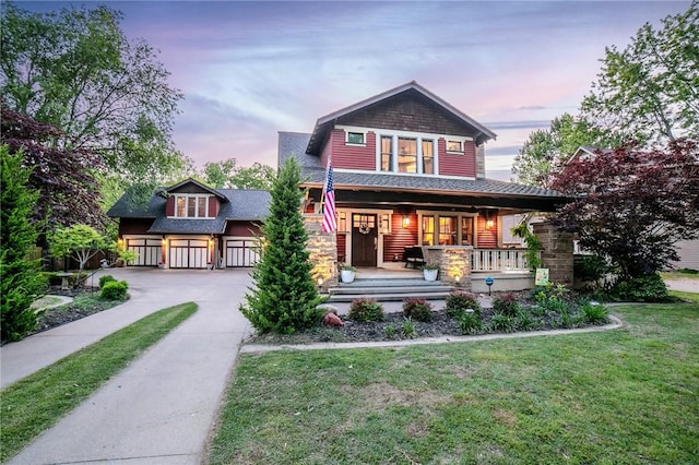 back of house with covered porch, concrete driveway, a shingled roof, and a lawn