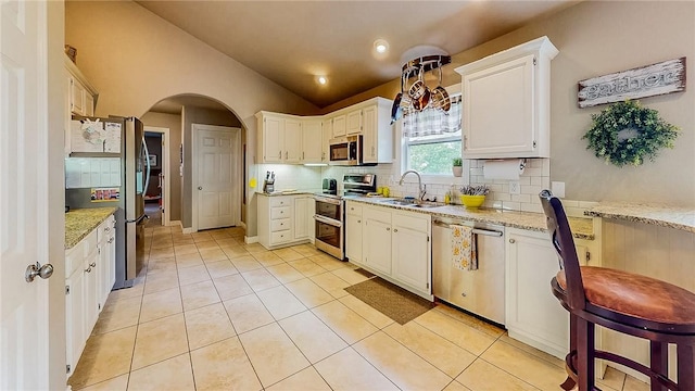 2341 N Fox Trl, Fayetteville, AR 72703 - kitchen with lofted ceiling, a sink, decorative backsplash, arched walkways, and appliances with stainless steel finishes