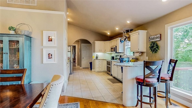 2341 N Fox Trl, Fayetteville, AR 72703 - kitchen featuring visible vents, a kitchen breakfast bar, arched walkways, light countertops, and appliances with stainless steel finishes