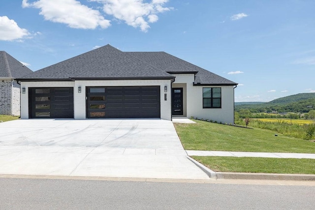 view of front facade with brick siding, an attached garage, concrete driveway, a front yard, and roof with shingles