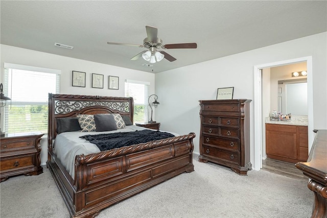 2300 Double Bogey Ln, Farmington, AR 72730 - bedroom featuring visible vents, baseboards, ceiling fan, ensuite bath, and light carpet