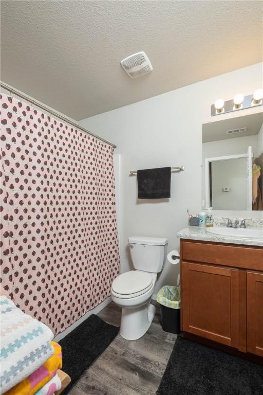 2300 Double Bogey Ln, Farmington, AR 72730 - bathroom featuring toilet, wood finished floors, vanity, a textured ceiling, and visible vents