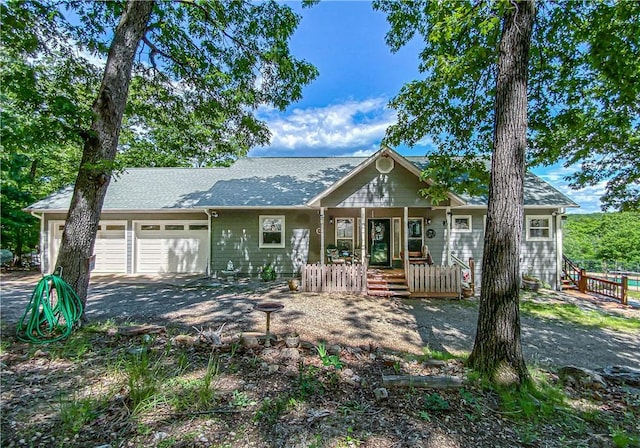 view of front facade featuring covered porch, fence, an attached garage, and aphalt driveway