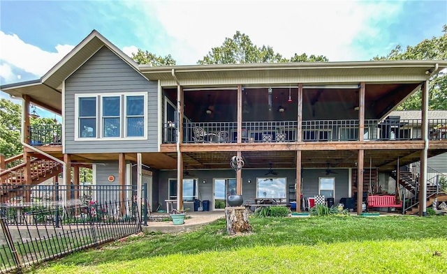 rear view of property featuring a lawn, stairs, a wooden deck, and fence