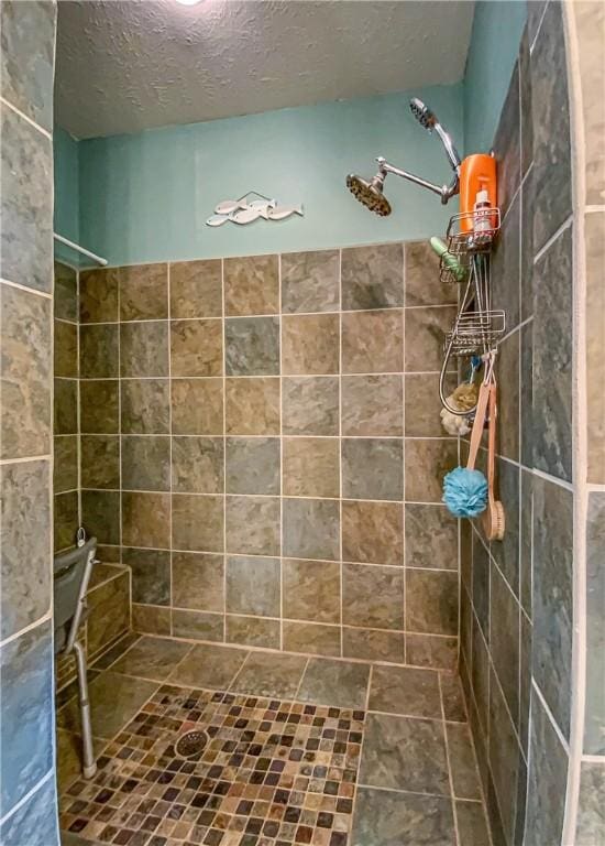 full bath with a textured ceiling and a tile shower