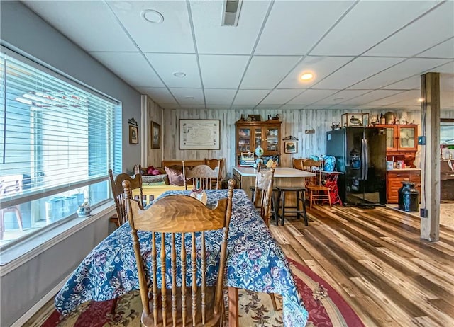 dining room with a drop ceiling, visible vents, and wood finished floors