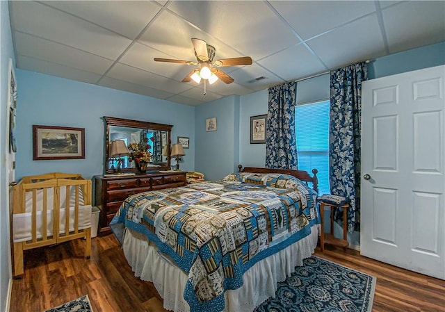 bedroom with wood finished floors, a ceiling fan, and a paneled ceiling