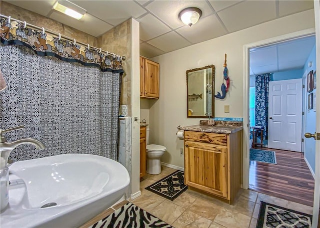 bathroom featuring toilet, a drop ceiling, a shower with curtain, a sink, and tile patterned floors