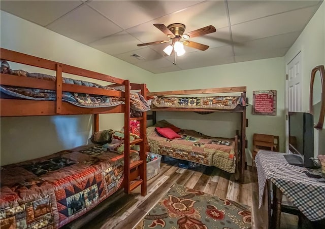 bedroom with ceiling fan, visible vents, and wood finished floors