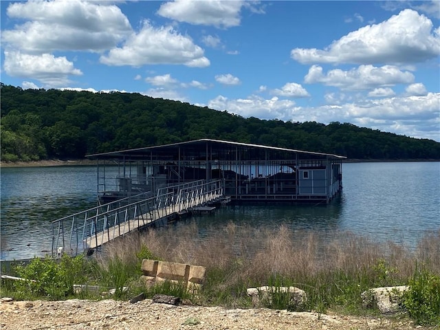 view of dock with a water view and a forest view