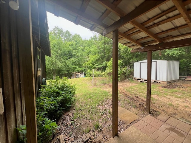 view of yard featuring an outbuilding, a shed, a forest view, and a patio