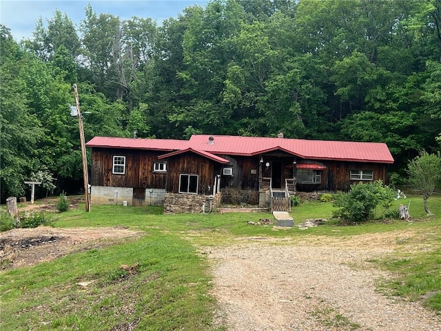 view of front of house featuring metal roof, a forest view, a front lawn, and board and batten siding