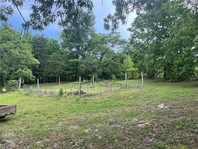 view of yard featuring a wooded view and fence