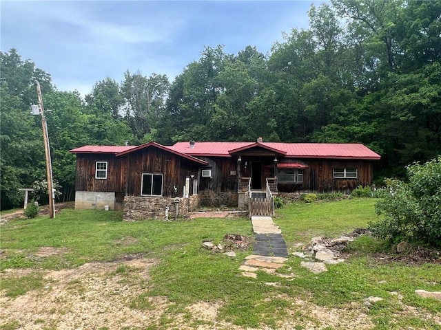 view of front facade featuring metal roof, a front lawn, and board and batten siding